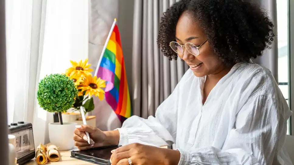 Donna di colore che scrive sullo sfondo ha una bandiera arcobaleno